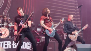 Alter Bridge performing on a festival stage in front of their banner